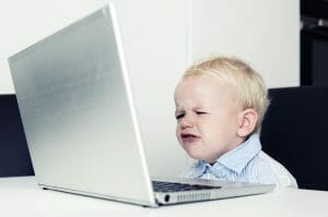 Little boy is sitting in front of a big laptop